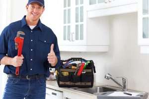 friendly plumber with a wrench and thumbs up after working on kitchen sink