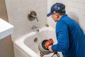 all service plumbers employee servicing a bath tub drain