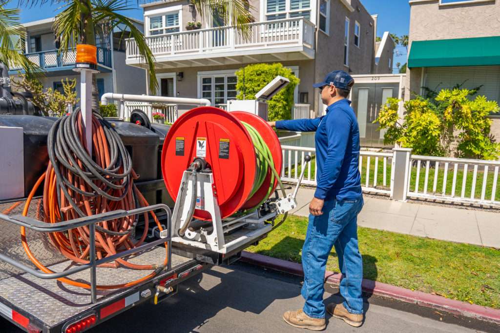 Technician working from the hydro jetting trailer outside a home
