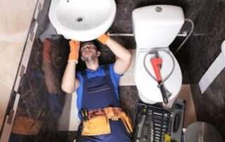 Professional Plumbers - plumber working underneath a sink in a bathroom